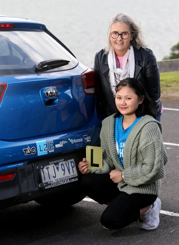 cogg_l2p_driver_010.jpg person holding L plates in front of a car with mentor standing behind them