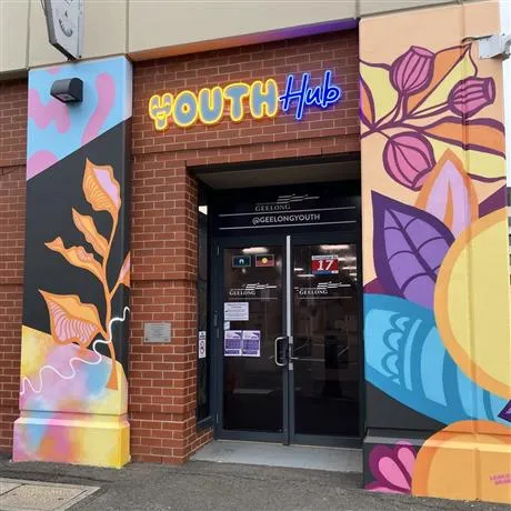 The Nest Youth Hub front Front of The Nest Youth Hub with neon signage and floral mural on pillars either side of entrance