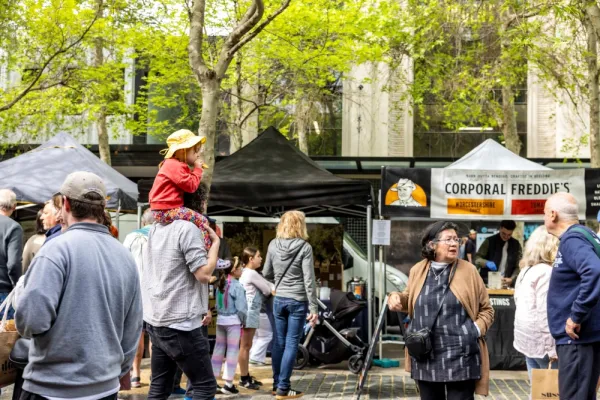 Crowds at Geelong City Market Man carries child on shoulders through market crowds past stalls