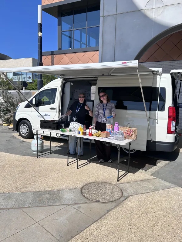 Mobile Youth Hub white van with two people standing under the annex with a table and bbq
