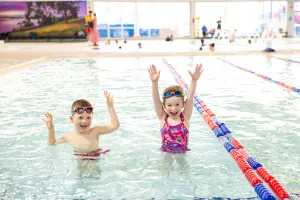 Webstar’s Swim School Two children in the pool, with their arms in the air